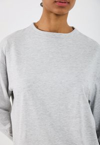 Grå hettegenser med rund hals, lange ermer og en myk tekstur. Enkelt design uten mønstre eller synlige detaljer.
