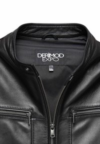 Zwarte leren jas met een hoge kraag, ritssluiting aan de voorkant en twee ritszakken op de borst. Het binnenlabel leest "DERIMOD EXPO" maat L.