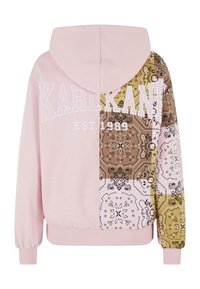 Hettegenser i lys rosa bomull, med en blandet stoffdesign med brunt og mønstre på den ene siden. Hvit merkevare på forsiden.