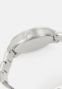 Orologio in acciaio inossidabile argentato con finitura lucida e spazzolata. Presenta una cassa rotonda, una corona e un design con bracciale a maglie.