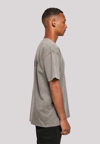 Gray, oversized T-shirt made of soft cotton with a faded texture and crew neckline. Features short sleeves and minimal branding on the back.