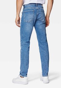 Blå denimjeans med smal passform, med två bakfickor och en standard midja, i kombination med vita sneakers.