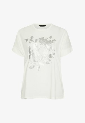 Camiseta blanca de manga corta con un diseño de hoja metálica plateada en el frente. La tela parece suave y tiene un corte holgado.
