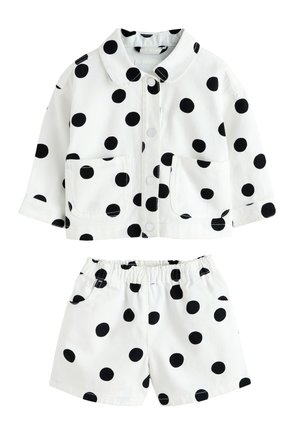 Biely set detskej bundy a krátkych nohavíc s veľkými čiernymi bodkami, zapínanie na gombíky vpredu, dve predné vrecká na bunde, elastický pás na krátkych nohaviciach.
