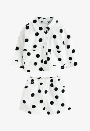 Hvid jakke og shorts i størrelse til småbørn med store sorte prikker, knaplukning foran, to forlommer på jakken, shorts med elastisk talje.