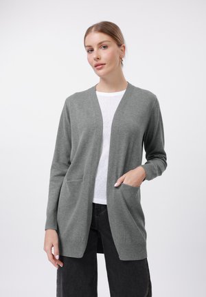 Light grey cardigan in soft fabric, featuring a V-neck, open front, two front pockets, and ribbed cuffs. Paired with a white shirt and black pants.