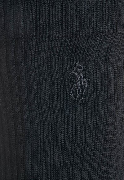 Melnas ribotas zeķes, kas izgatavotas no mīksta adījuma materiāla, ar mazu izšūtu zirdziņa logotipu sānos.