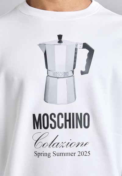 Sudadera blanca con un gráfico de una cafetera italiana de acero inoxidable y el texto que dice "MOSCHINO Colazione Primavera Verano 2025."