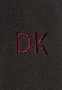 Mørkegrå fleece-stof med en blød tekstur, prydet med broderede initialer "DK" i bourgogne tråd. Enkel design, ingen yderligere mønstre.