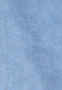 Tissu tissé bleu clair avec un motif texturé visible composé de petits fils régulièrement espacés.