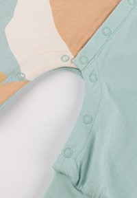 Cotton onesie featuring a color-block design in mint, beige, and cream. Snap closures at the shoulder and leg openings for easy dressing.