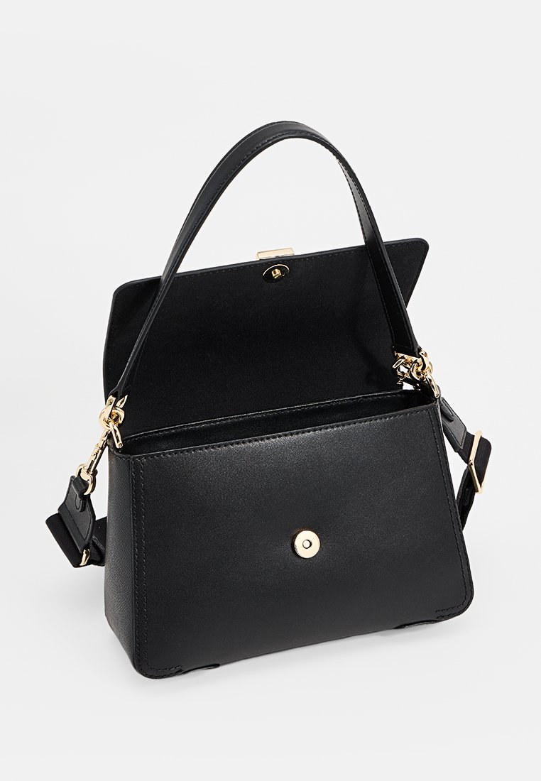 Sac à main en cuir noir au design structuré. Doté d'une anse supérieure, d'une bandoulière réglable, de quincaillerie dorée et d'une fermeture à pression. L'intérieur est ouvert.