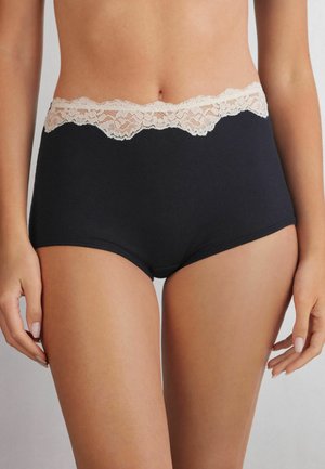 Zwarte hoge taille slips van ribstof, met een delicate lichte kantafwerking aan de tailleband. Glad materiaal, volledige dekking.