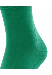 Grüne Baumwollsocke mit glatter Textur, geripptem Bündchen und nahtloser Zehenpartie, die ein passgenaues Knöchel-Design und einen weichen, elastischen Stoff hervorhebt.