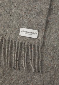 Grau gestreifter Schal aus Wolle mit subtilen, mehrfarbigen Sprenkeln und fransigen Kanten; das Etikett trägt die Aufschrift "Johnstons of Elgin, Made in Scotland."
