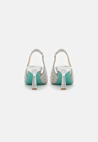 Talons ouverts argentés avec un dos orné, des accents turquoise et un talon métallique fin. Présente des détails complexes le long des bords.