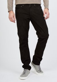 Kapeat mustat istuvat housut, jotka on valmistettu pehmeästä kankaasta ja joissa on viisi taskua, nappisuljenta ja yhdistetty vaaleanharmaiden mokkanahkakenkien kanssa, joissa on nauhakiinnitys.