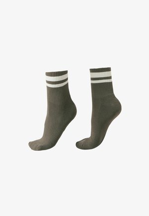 Para ciemnozielonych skarpetek za kostkę z dwoma białymi poziomymi paskami u góry, na białym tle.