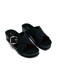 Sandalias de cuña de ante negro con correas cruzadas y un acento de hebilla dorada; suela texturizada y plantilla acolchada para mayor comodidad.