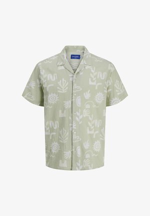 Short-sleeve, light green shirt with white abstract patterns, paired with light blue denim shorts. Black and white sneakers complete the outfit.