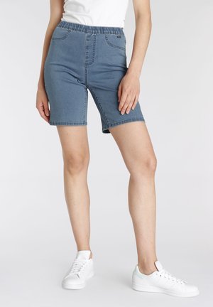 Denim Bermuda shorts in light blue, featuring an elastic waistband, front pockets, and a slim fit, paired with white sneakers.