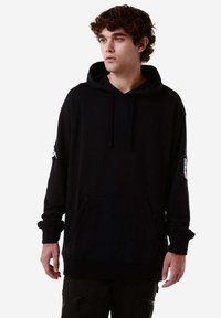 Felpa nera con cappuccio e maniche lunghe, tasca frontale e logo sulla manica sinistra. Realizzata in tessuto morbido con una vestibilità rilassata.