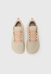 Pāris bēša krāsas Altra FWD VIA 2 skriešanas apavu ar persiku krāsas šņorzīmēm, skatīti no augšas uz balta fona.