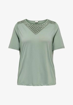 Světle zelené tričko s krátkým rukávem a krajkovým detailem na rameni a výstřihu, vyrobené z jemné tkaniny, s volným střihem a kulatým lemem.