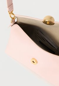 Világos rózsaszín bőrből készült kézitáska íves formával, aranyszínű fém díszítésekkel és egyetlen mágneszárral. Belsejében kártyatartók és puha bélés található.