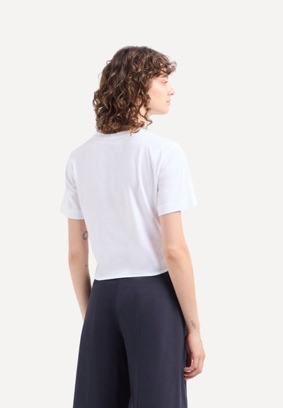 Witte katoenen t-shirt met een ontspannen pasvorm, korte mouwen en een ronde halslijn, van achteren afgebeeld tegen een neutrale achtergrond.