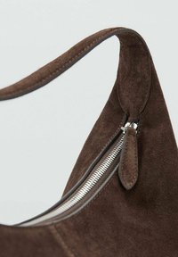 Brązowa torebka z zamszu z zakrzywionym paskiem, wyposażona w srebrny zamek błyskawiczny i gładki suwak. Skupienie na fakturze i eleganckim designie.