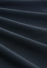 Textured fabric in dark navy blue, featuring a woven pattern with visible threads, lays in multiple folds. Soft, durable material.