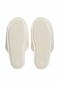 Witte pluizige slippers met gestructureerde rubberen zolen waarop "Tommy Hilfiger" en maat 39/40 zijn gedrukt, getoond vanuit de onderkant.