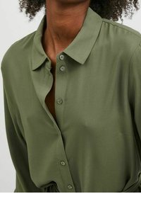 Olivgrön skjorta med knappar och klassisk krage, tillverkad av mjukt tyg. Har en avslappnad passform och en subtil textur över hela plagget.