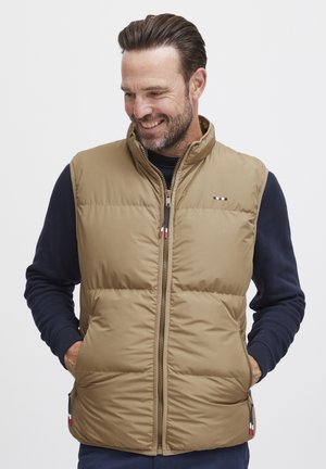 Vest puffer bej cu guler înalt, fermoar frontal și buzunare laterale. Prezintă un logo subtil al mărcii în roșu, alb și albastru pe piept.