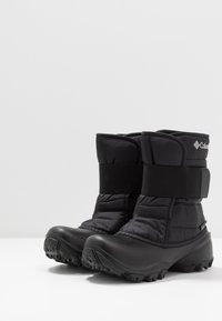 Mustat eristetytsääreet, joissa pehmustettu yläosa, säädettävä tarranauhakiinnitys ja kuvioitu kumipohja pitoon. Vedenpitävä muotoilu.