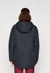 Temno modra vodoodporna jakna s kapuco, dolgi rokavi, zožen pas in daljši rob na hrbtu za boljšo pokritost.