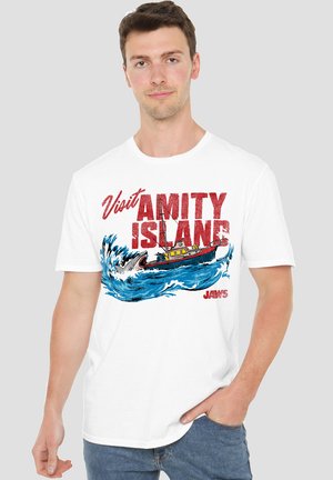 White cotton t-shirt featuring a graphic of a fishing boat in waves with "Visit Amity Island" and "Jaws" text in red and blue.