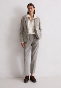 Light gray textured suit featuring a tailored blazer and fitted trousers. Paired with a cream striped shirt and brown slip-on shoes.