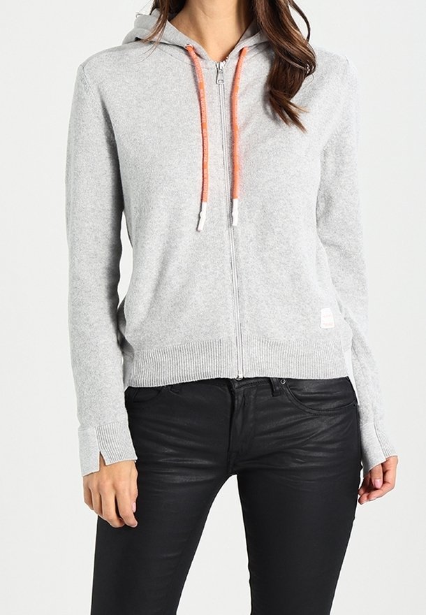 Szara bluza rozpinana na zamek z pomarańczowymi sznurkami, ściągaczami na mankietach i na dole. Gładka faktura i casualowy design, w połączeniu z czarnymi, dopasowanymi spodniami.