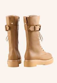 Tan leren veterschoenen met een ronde neus, dikke, platformzool, zijrits, gespaccent en een gestructureerde bovenkant.