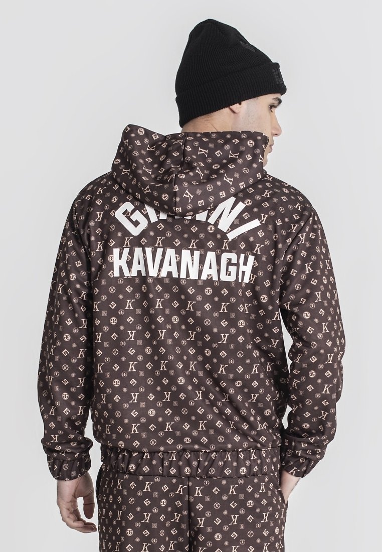 Chaqueta marrón con un patrón de logo repetido en un color beige claro, con capucha y puños elásticos. La parte trasera muestra "GIANNI KAVANAGH" en texto blanco.