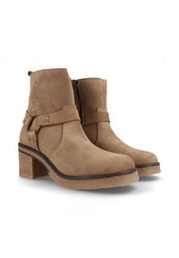 Botines de ante marrón con un tacón grueso, que cuentan con una cremallera lateral, una correa ajustable con detalles de hardware y una suela texturizada.