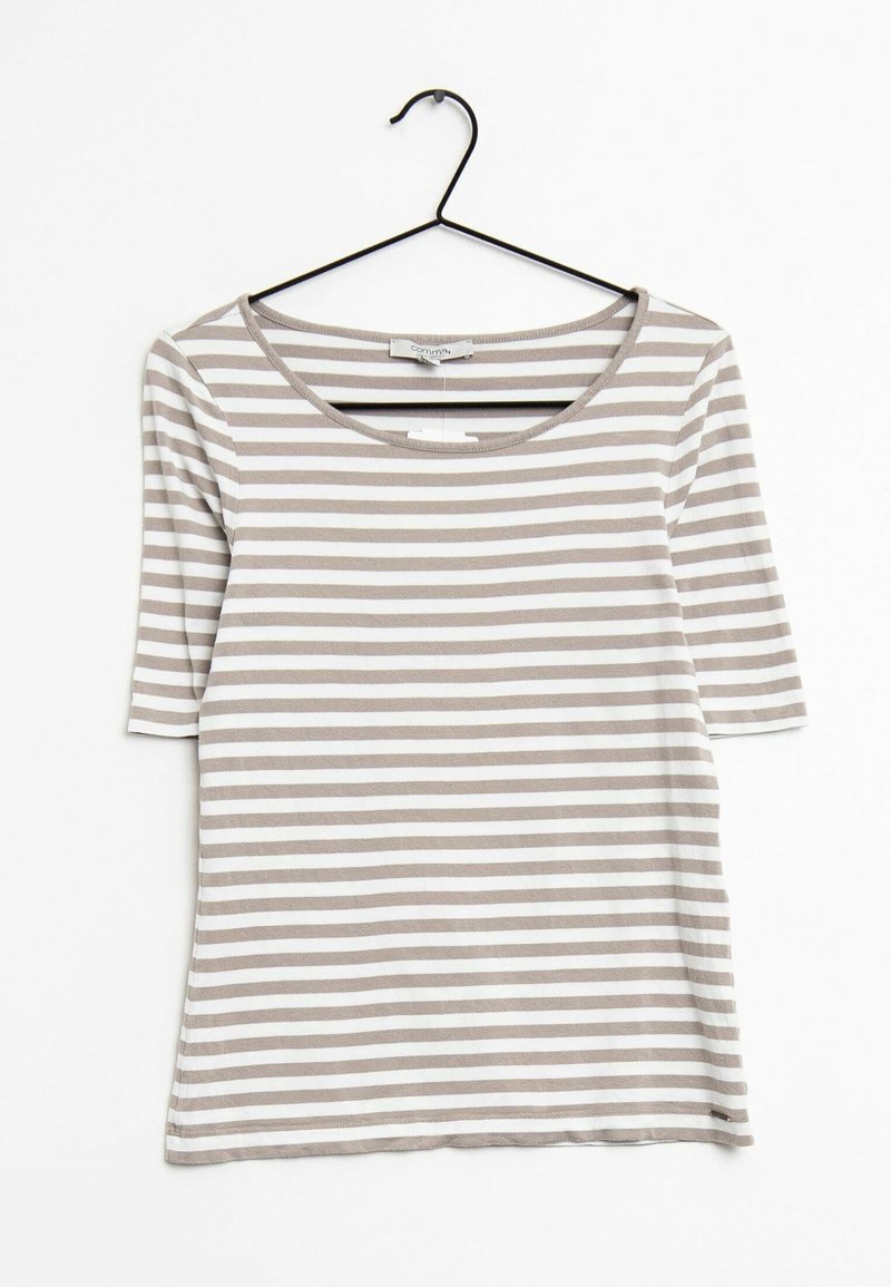 Chemise à rayures horizontales beige clair et blanches pour femme, à manches mi-longues, suspendue à un cintre noir sur un fond blanc.