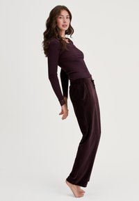 Bordeaux langemouwen geribbelde shirt met kanten accenten, gecombineerd met bijpassende losvallende broeken van zachte stof met zijzakken.