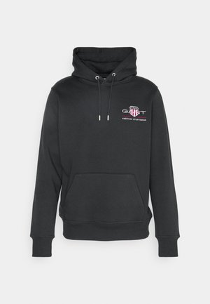 Haut à capuche noir en tissu doux, avec une poche kangourou à l'avant, des cordons de serrage ajustables et un petit logo brodé sur la poitrine.