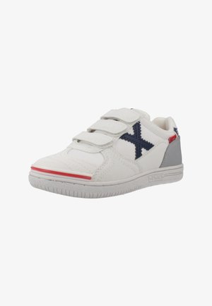 Zapatilla de tela blanca con acentos en azul marino, talón gris, franja roja y tres correas de Velcro para un ajuste seguro. Detalles texturizados en los laterales.