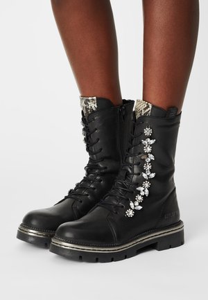 Black leather combat boots with a lace-up design, silver hardware, rhinestone accents on the side, and a snakeskin-patterned collar.