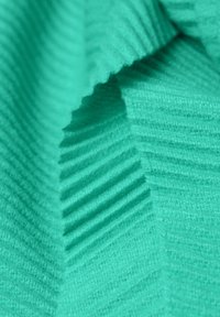 Teal strikket stof med tekstureret ribbing. Har lodrette linjer og en blød, fuzzy overflade, der skaber dybde og dimension.