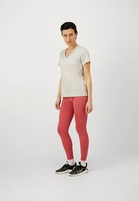 Camiseta de color gris claro con cuello en V combinada con leggings ajustados rosa, complementada con zapatillas deportivas negras con detalles blancos. Diseño simple.